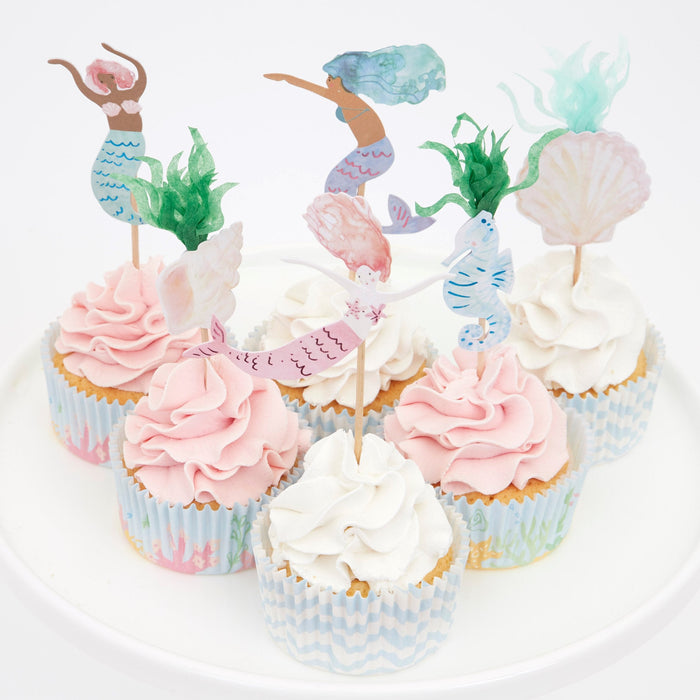Mermaid Cupcake Kit with decorated cupcakes featuring watercolor-style mermaid, seahorse, shell, and seaweed toppers in patterned cupcake cases.