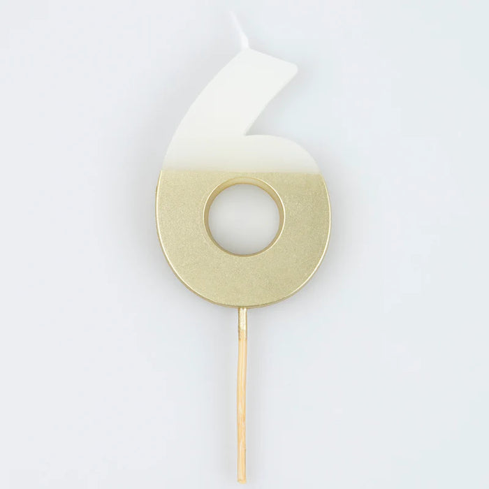 White number 6 cake candle with metallic gold dipped finish and wooden pick on a white background.