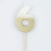 White number 6 cake candle with metallic gold dipped finish and wooden pick on a white background.