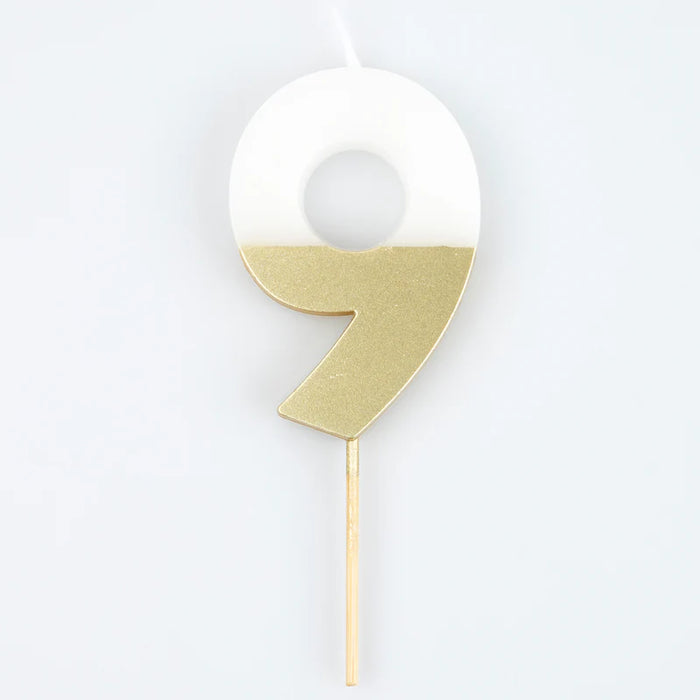 White number 9 cake candle with metallic gold dipped finish and wooden pick on a white background.