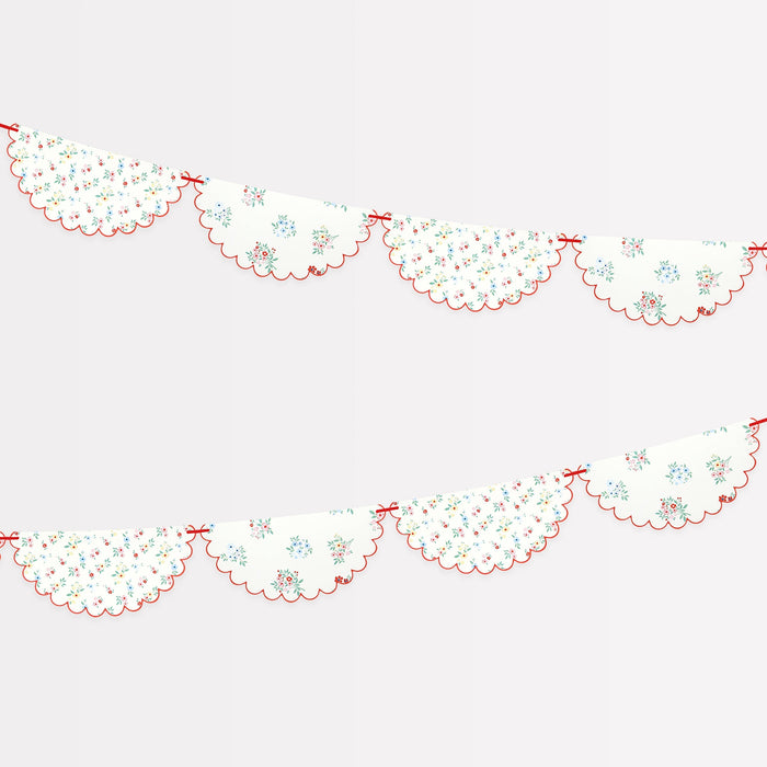 Ditsy Posy Paper Garland with scalloped floral pennants, red trim, and bow-style details on a white background.