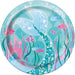 Round turquoise paper plate featuring an underwater mermaid scene with a pink castle, colorful fish, seaweed, and a mermaid tail with sparkles.