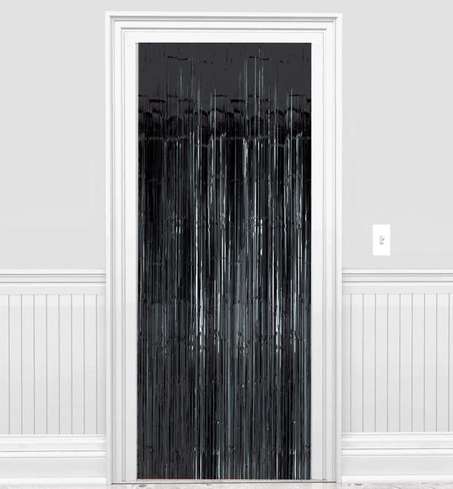 Black metallic fringe curtain with vertical streamers hanging in a white doorway frame against white walls with wainscoting.