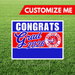 Graduation-themed sign with 'Congrats Grad 2026' text on a grass background