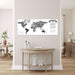 Black and white world map poster titled "Called to Serve" with Matthew 28:19 scripture quote, displayed on a pale pink wall above a light wood console table in a modern home interior.
