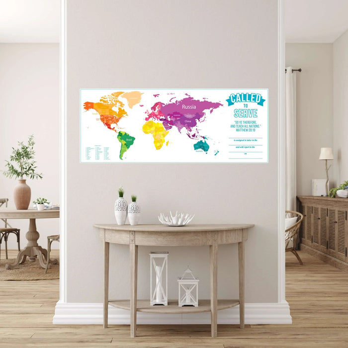 Colorful world map wall chart with rainbow-colored continents, "Called to Serve" text, and Matthew 28:19 Bible verse displayed above a light wood console table in a bright living room.