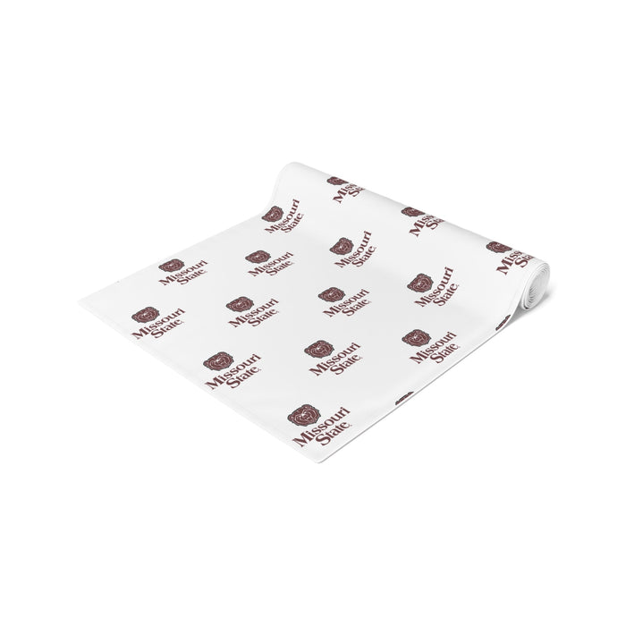 White table runner with repeating Missouri State logo and text pattern in burgundy, rolled and displayed at an angle.