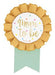 Gold pleated rosette badge with mint green ribbon banner featuring "Mom to be" text in gold lettering and small decorative dots.