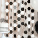 Hanging garland made of connected black, white, and gray hexagonal paper shapes strung vertically as party decoration backdrop.