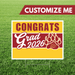 Graduation-themed sign with 'Congrats Grad 2026' on a grass background