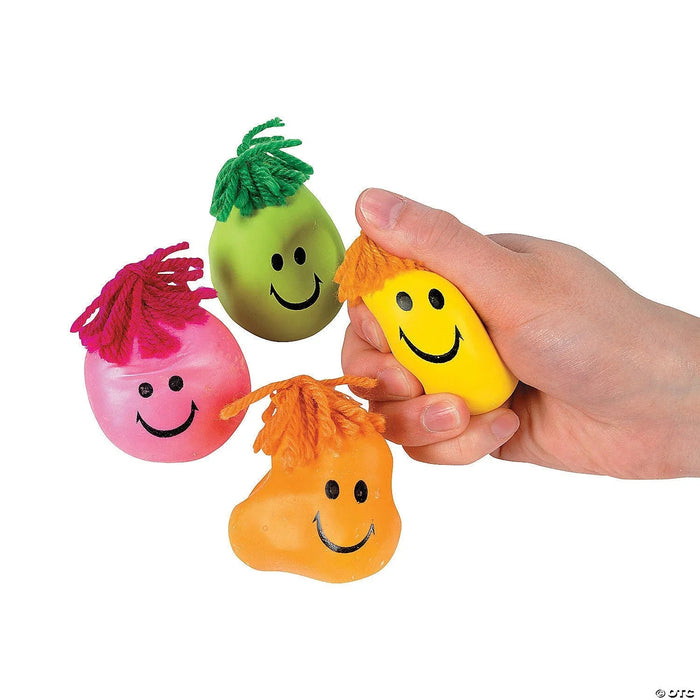 Four squishy stress toys in neon colors with smiling faces and colorful yarn hair, held in a hand against a white background.
