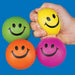 Four neon-colored stress balls with smiley faces in green, yellow, orange, and pink, displayed against a blue background with one held in a hand.