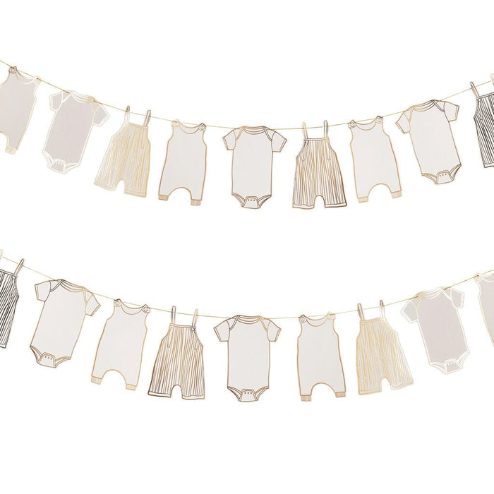 Two horizontal clotheslines strung with various neutral-toned baby garments including onesies, rompers, and overalls held by clothespins in a beige and cream color palette.