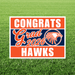 Graduation-themed sign with 'Congrats Grad 2026 Hawks' on a grass background