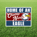 Rectangular yard sign with navy blue and burgundy stripes featuring white text reading "HOME OF AN Olathe North EAGLE" alongside an eagle head logo in navy, white, and gold.