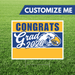 Graduation-themed customizable sign with 'Congrats Grad 2026' text on a grass background