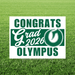 White yard sign with green text reading "CONGRATS Grad 2026 OLYMPUS" and a decorative leaf logo, displayed on green grass.