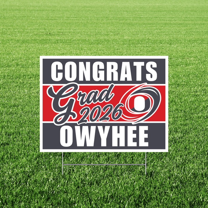 Red, white, and gray yard sign with "Congrats Grad 2026" text and "Owyhee" at bottom, displayed on grass with metal stake supports.