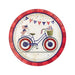 Red paper dessert plate featuring a blue bicycle decorated with American flags and a basket, surrounded by patriotic bunting and confetti on a cream background.