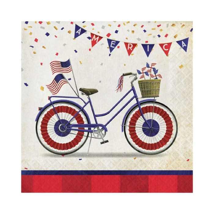 Blue bicycle with red and white striped wheels, American flags, and a gold basket on cream napkins decorated with patriotic bunting and confetti.