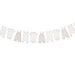 Beige and pink baby clothing items hanging on a clothesline string, including onesies, bodysuits, overalls, and rompers with decorative clothespins.
