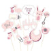 Set of 13 pink baby shower photo booth props on sticks including stork, bottle, pacifier, bunny, rattles, bibs, socks, bow, duck, glasses, and speech bubbles reading "girl," "oh baby," and "Mummy to be.