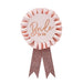 Pink rosette badge with "Bride to be" text in rose gold lettering, featuring a ruffled circular center and two glittery rose gold ribbon tails hanging below.