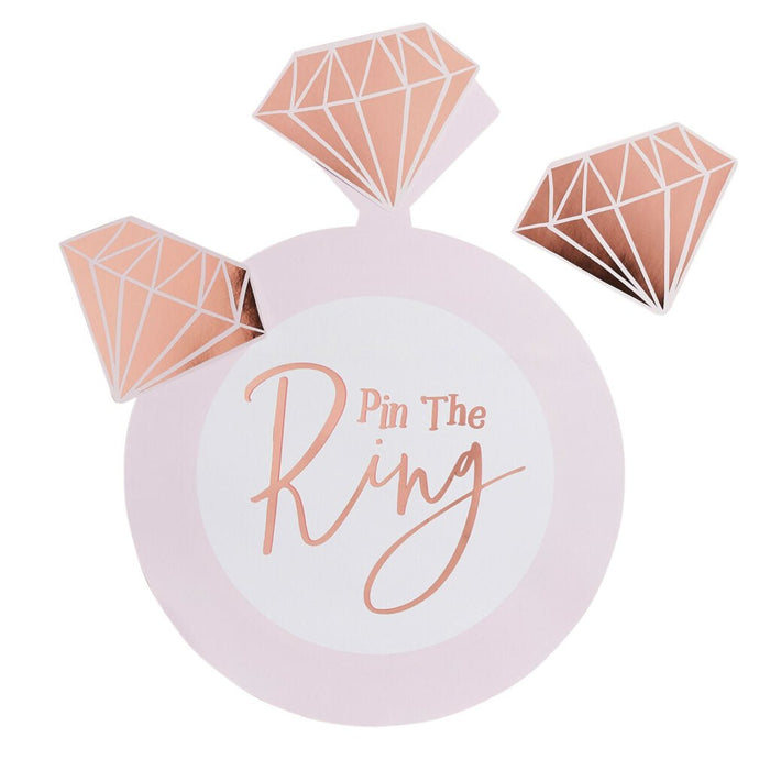 Rose gold geometric diamond shape with pale pink circular base displaying "Pin The Ring" text, accompanied by three faceted diamond cutouts for a bridal shower game.