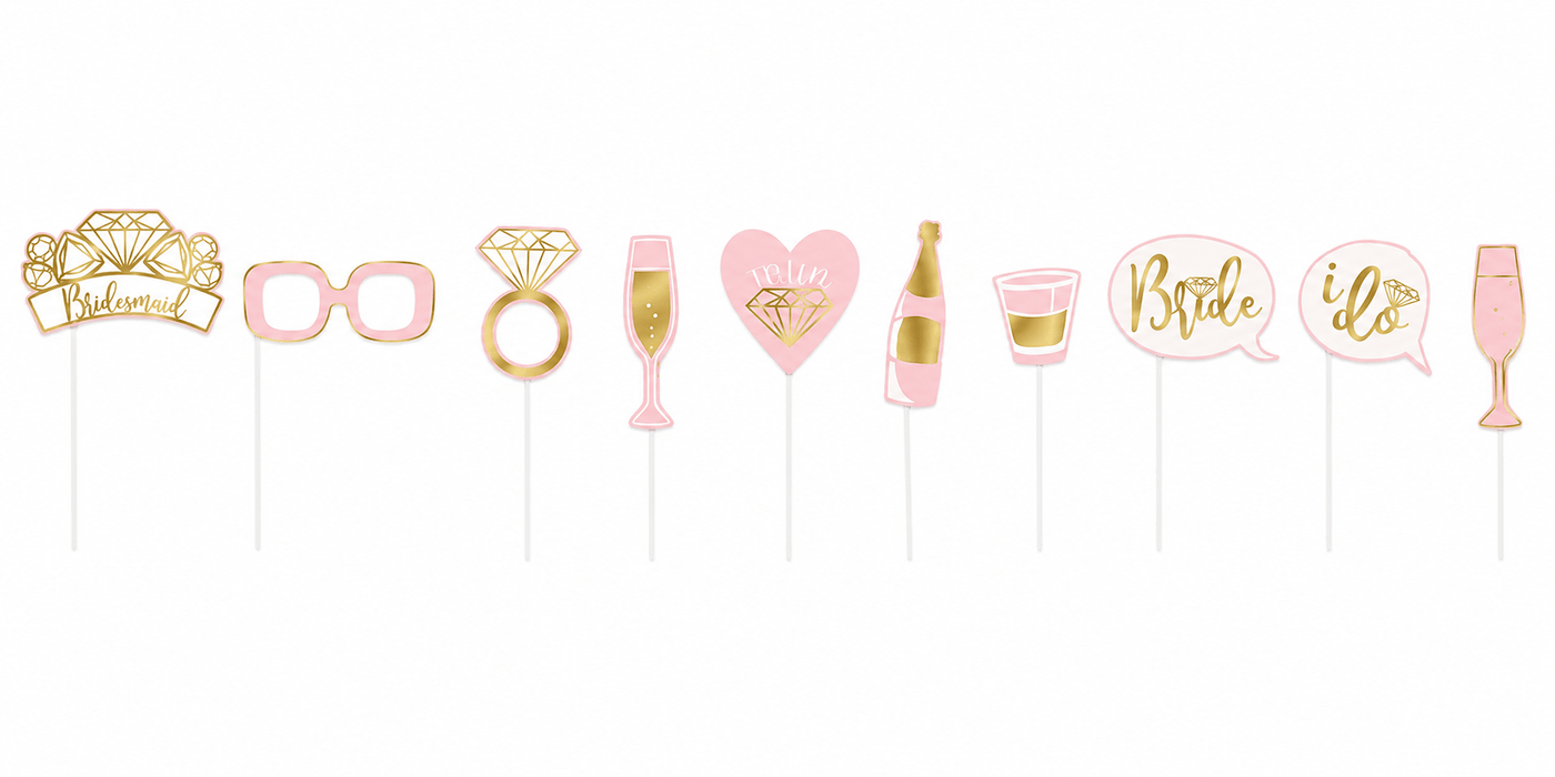 Ten pink and gold bachelorette party photo booth props on sticks, including glasses, rings, champagne flutes, a bottle, hearts, and speech bubbles with text like "Bride" and "I do".