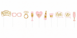 Ten pink and gold bachelorette party photo booth props on sticks, including glasses, rings, champagne flutes, a bottle, hearts, and speech bubbles with text like "Bride" and "I do".
