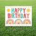 Colorful yard sign with "Happy Birthday" text in red, teal, and orange letters, decorated with yellow suns and three rainbow designs with leaf accents on a white background.