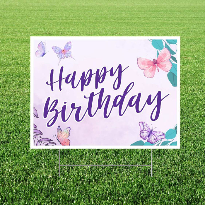 Outdoor yard sign featuring "Happy Birthday" in purple script lettering centered on a cream background, decorated with watercolor butterflies in pink and purple tones and teal leaves in the corners.