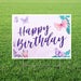 Outdoor yard sign featuring "Happy Birthday" in purple script lettering centered on a cream background, decorated with watercolor butterflies in pink and purple tones and teal leaves in the corners.