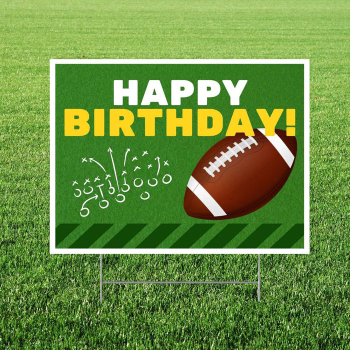 Lawn yard sign displaying "Happy Birthday" in white and yellow text on green grass background with football and play diagram illustration.