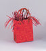Red glitter gift bag with curled ribbon handles standing upright against a gray background.