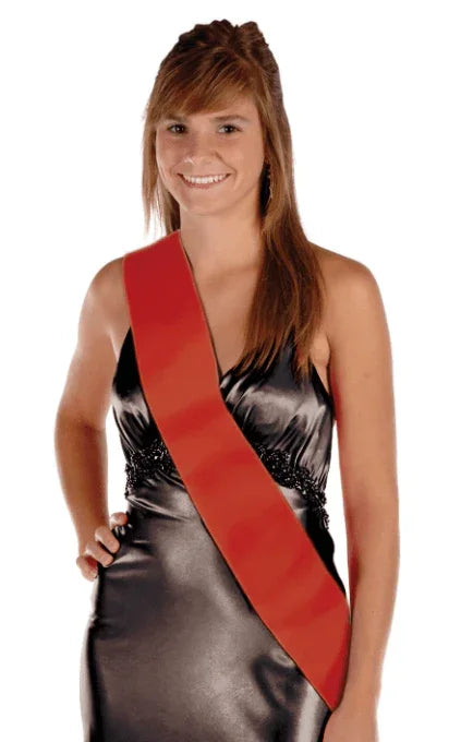 Woman wearing a black satin wrap dress with a red satin sash draped diagonally across the torso.