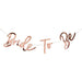 Rose gold metallic banner with cursive lettering reading "Bride to Be" connected by string.