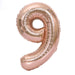 Rose gold foil balloon shaped like the number 9 with a shiny metallic finish and ribbed texture throughout.