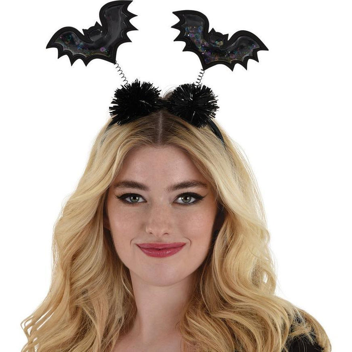 Black bat-shaped head bopper with colorful sequins and two black fuzzy pom-pom antennae on coiled springs, displayed on a blonde-haired model.