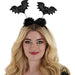Black bat-shaped head bopper with colorful sequins and two black fuzzy pom-pom antennae on coiled springs, displayed on a blonde-haired model.