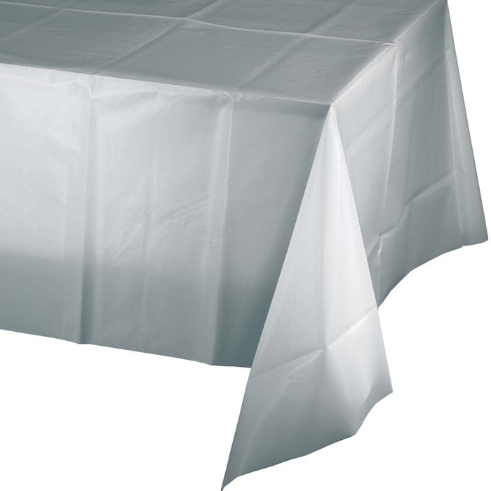 White plastic tablecloth with shimmering silver finish draped over a table, showing the rectangular shape and lightweight material typical of disposable party tableware.