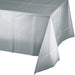 White plastic tablecloth with shimmering silver finish draped over a table, showing the rectangular shape and lightweight material typical of disposable party tableware.