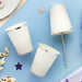 Three white paper cups with silver metallic trim arranged on a blue background alongside decorative stars and popcorn.