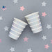Two silver iridescent foil striped paper cups with white bands arranged on a gray background surrounded by pink and white decorative stars.