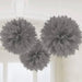 Three silver fluffy pompom decorations hanging from strings against a white wall and doorway.