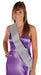 Woman wearing a purple satin wrap dress with a silver satin sash draped diagonally across the torso.