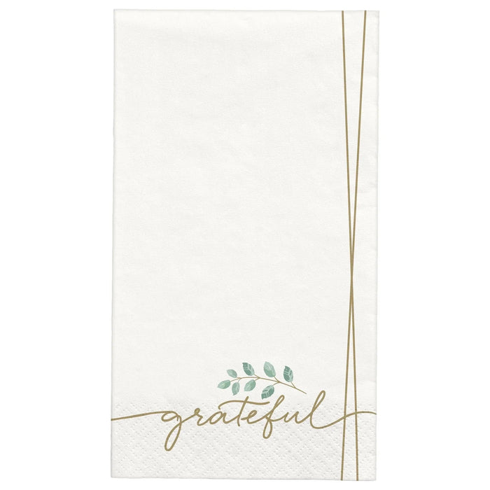 White paper guest towels with "grateful" written in gold script and a small green leaf sprig detail, featuring gold lines on the sides.