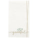 White paper guest towels with "grateful" written in gold script and a small green leaf sprig detail, featuring gold lines on the sides.