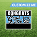 Graduation-themed sign with 'Congrats Grad 2026' on a grass background