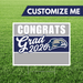 Graduation-themed yard sign with 'Congrats Grad 2026' text and customizable option on a grass background.